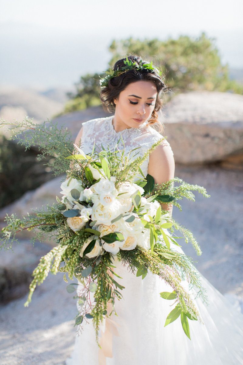 Bride holding bouquet in outdoor setting.