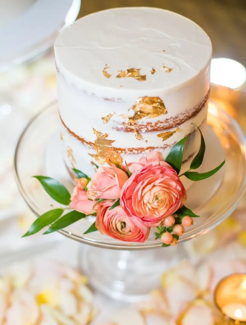 White cake with gold leaf and flowers.