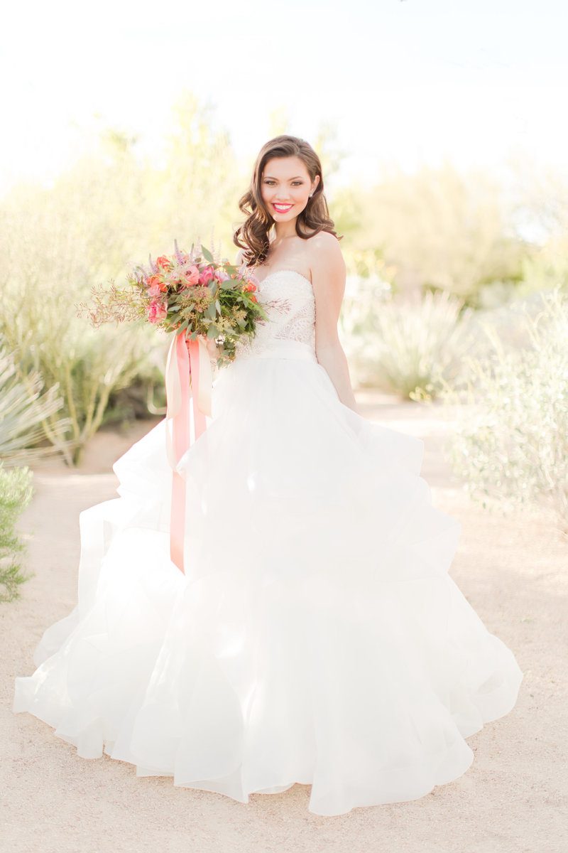 Bride holding bouquet in desert landscape.