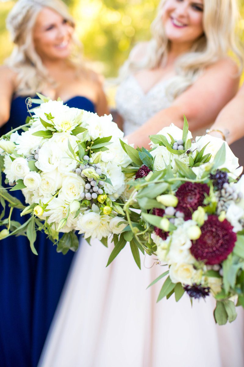 Women holding white and purple flower bouquets.