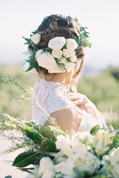 Bride with floral hairstyle holding bouquet.