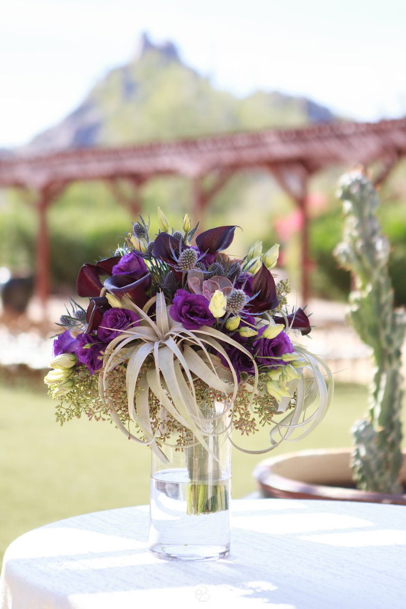 Purple floral arrangement on outdoor table.