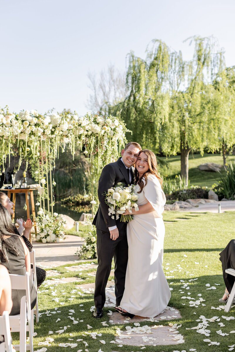 Bride and groom smiling at outdoor wedding.