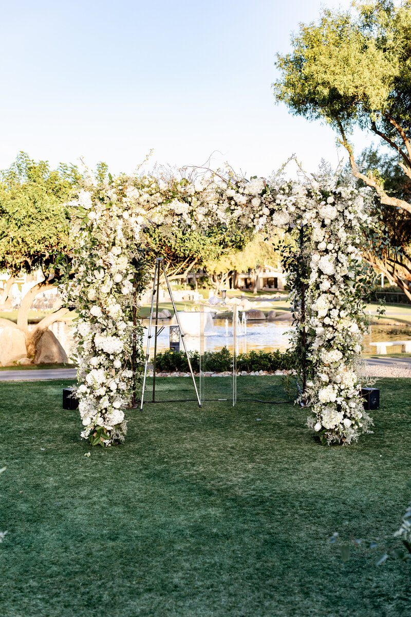 Floral arch in a sunny outdoor setting.